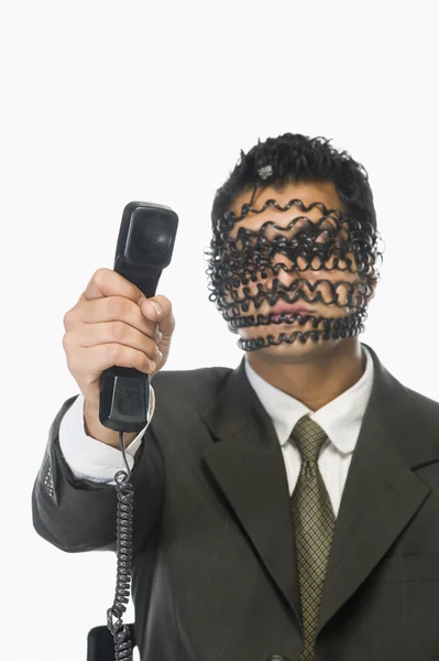 Homme d'affaires avec son visage couvert par le cordon du téléphone — Photo