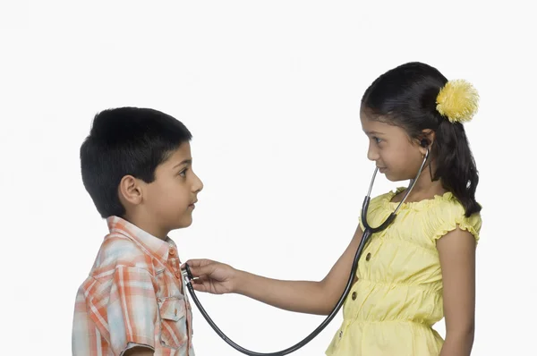 Ragazza esaminando un ragazzo con uno stetoscopio — Foto Stock
