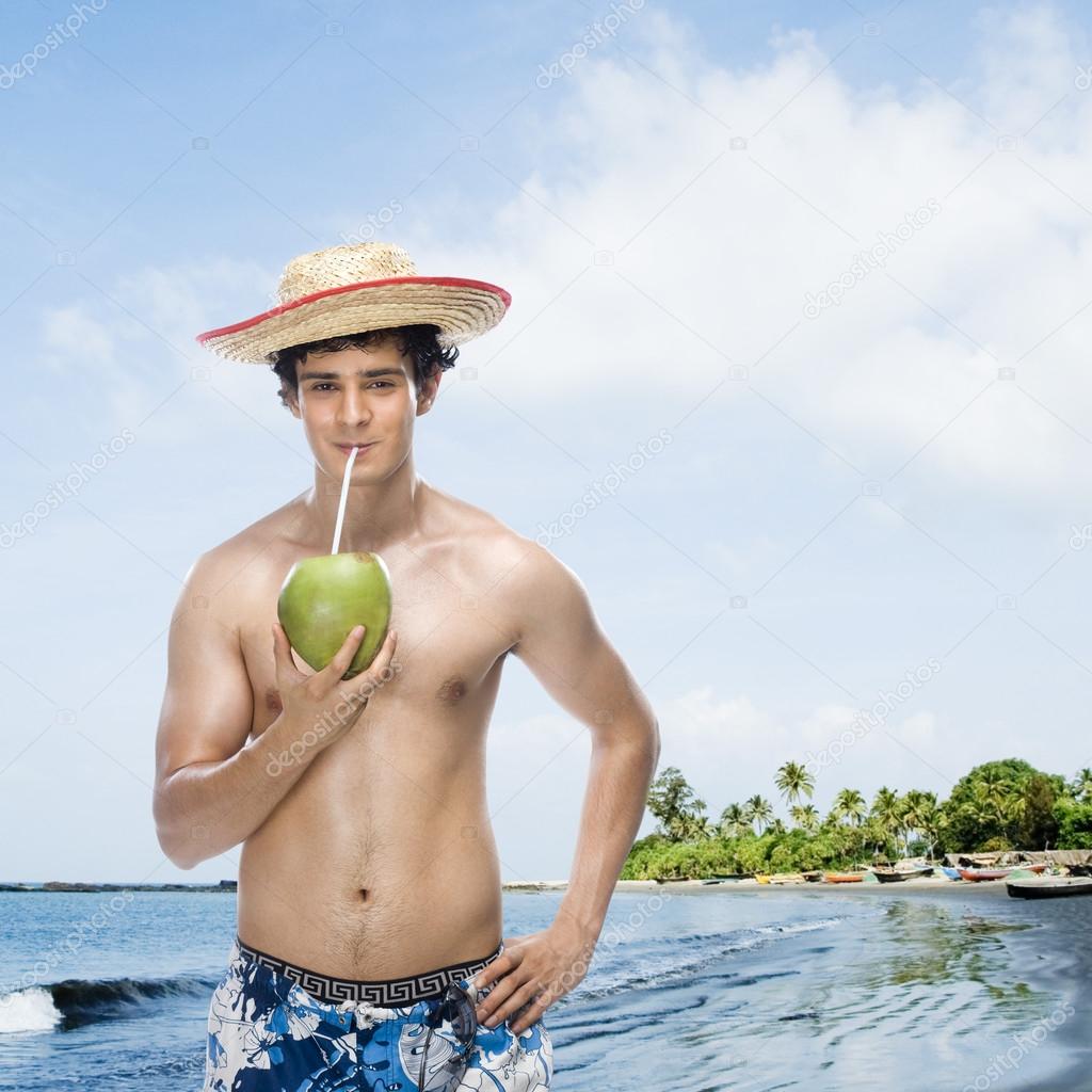 Man drinking coconut milk on the beach