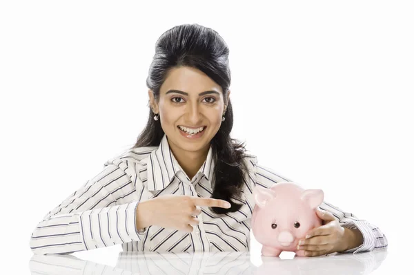 Empresaria apuntando hacia alcancía — Foto de Stock