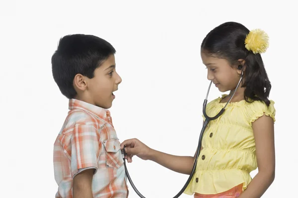 Chica examinando a un niño con un estetoscopio — Foto de Stock