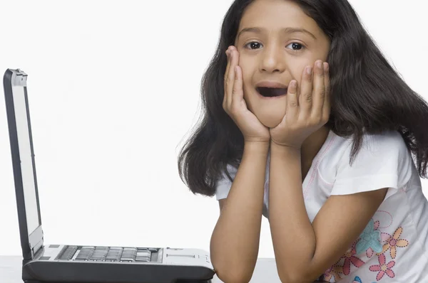 Girl sitting in front of a laptop in shock — Stock Photo, Image
