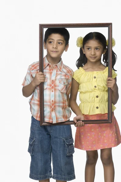 Menina e um menino segurando uma moldura vazia — Fotografia de Stock