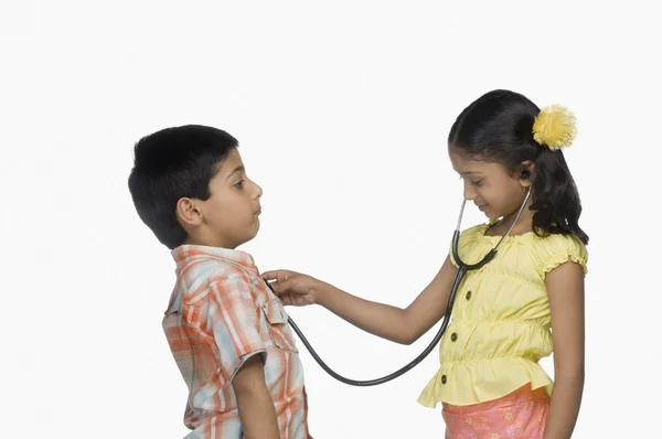 Ragazza esaminando un ragazzo con uno stetoscopio — Foto Stock