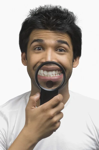 Man smiling in front of a magnifying glass — Stock Photo, Image