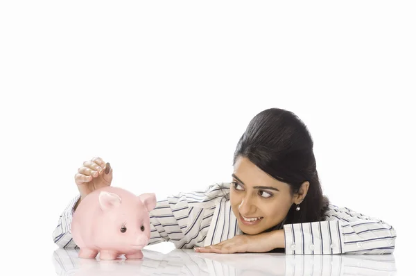 Businesswoman inserting a coin into a piggy bank — Stock Photo, Image
