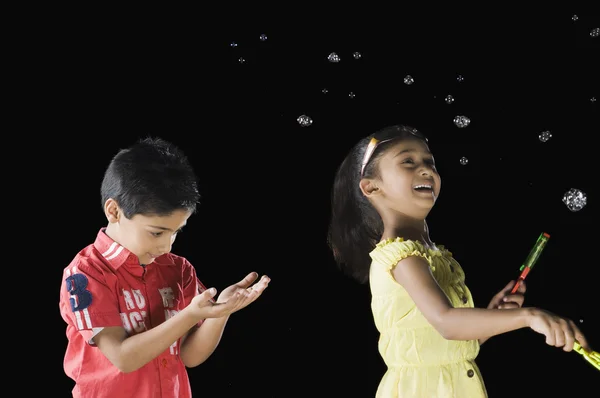 Ragazza soffiando bolle e un ragazzo guardando il suo palmo — Foto Stock