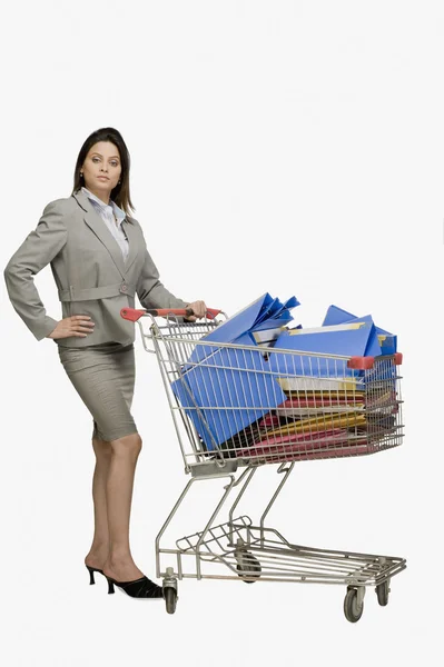 Businesswoman standing near a shopping cart filled with files — Stock Photo, Image