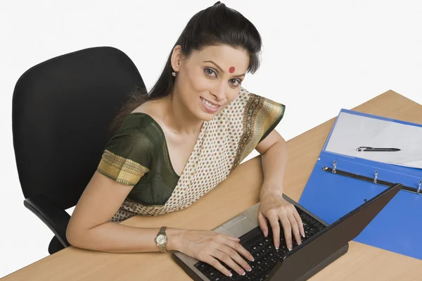 Bir ofiste bir dizüstü bilgisayar üzerinde çalışan iş kadını — Stok fotoğraf