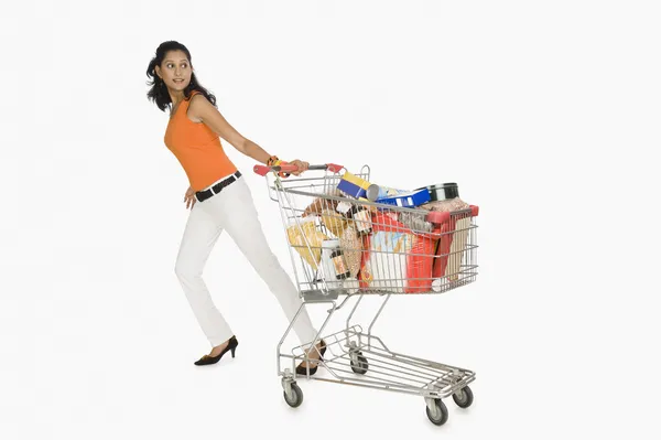 Mulher puxando um carrinho de compras — Fotografia de Stock