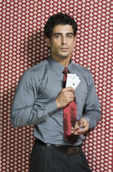 Hombre sosteniendo tres ases y fichas de juego — Foto de Stock