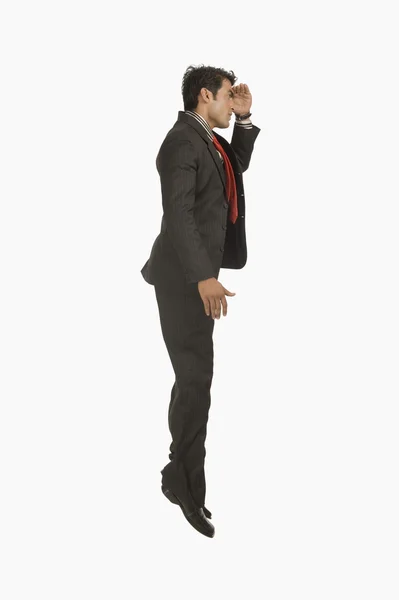 Businessman looking away with shielding his eyes — Stock Photo, Image