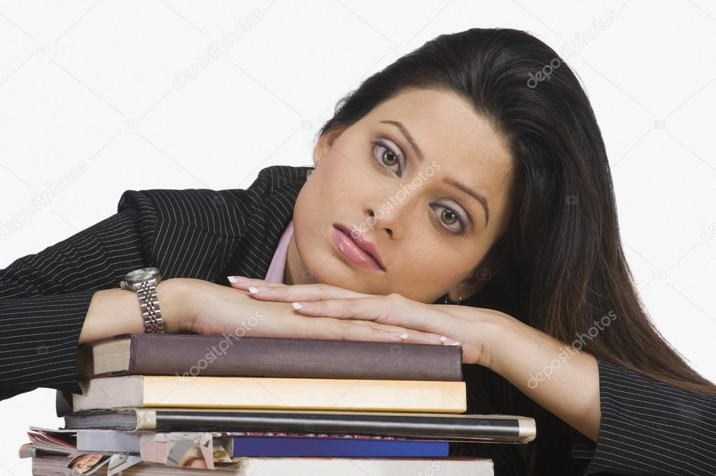 Businesswoman resting her face on books