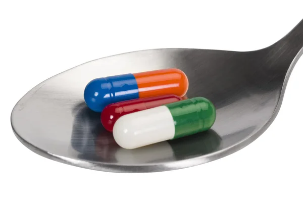Spoon with capsules — Stock Photo, Image
