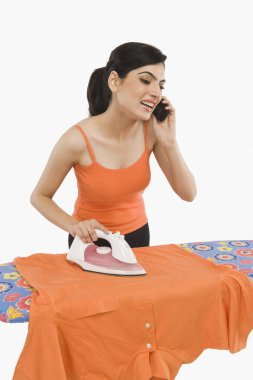 Ütü ve bir cep telefonu üzerinde konuşurken kadın