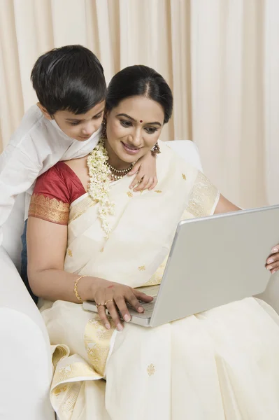 Vrouw met behulp van een laptop met haar zoon — Stockfoto