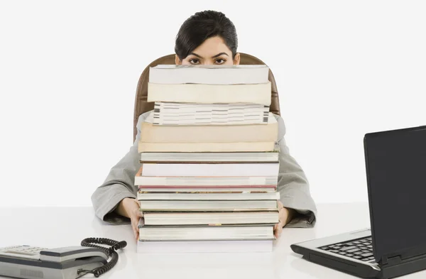 Businesswoman hiding behind a stack of books — Stock Photo, Image