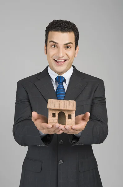 Businessman holding a model home — Stock Photo, Image