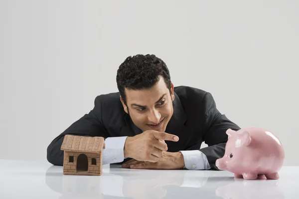 Businessman with a model home and a piggy bank — Stock Photo, Image