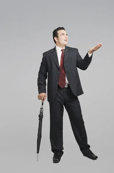 Businessman holding an umbrella and checking for rain — Stock Photo, Image