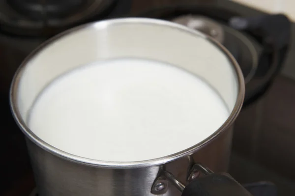 Milk in a saucepan on a gas stove burner — Stock Photo, Image