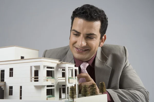 Podnikatel při pohledu na model domů v kanceláři — Stock fotografie