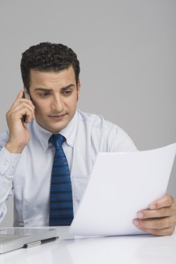 bir belge tutan ve bir cep telefonu üzerinde konuşurken işadamı