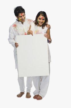 Çift bir afişini holi üzerinde tutan