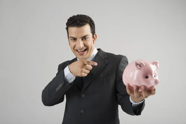 Portrait of a businessman pointing at a piggy bank — Stock Photo, Image