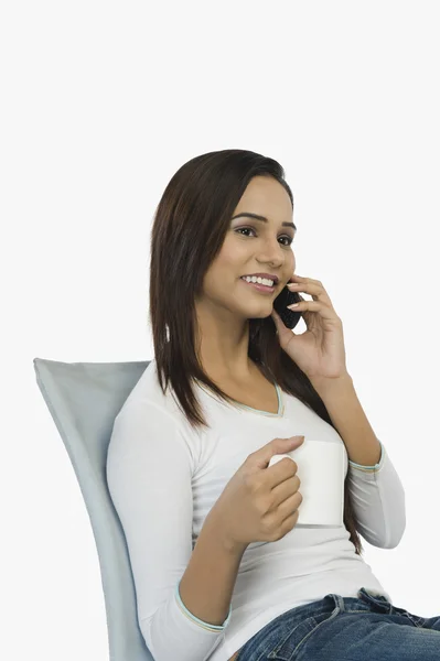 Woman talking on a mobile phone and drinking coffee — Stock Photo, Image