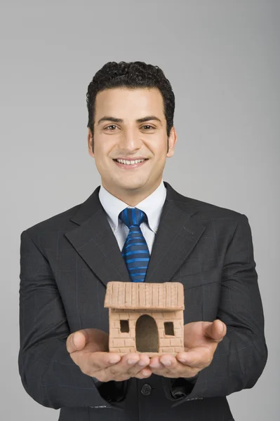 Businessman holding a model home — Stock Photo, Image