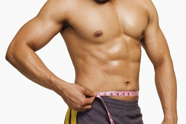 Mid section view of a man measuring his waist — Stock Photo, Image