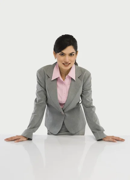 Businesswoman leaning on a desk — Stock Photo, Image