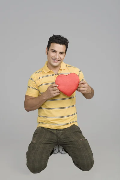 Hombre proponiendo con un regalo en forma de corazón —  Fotos de Stock