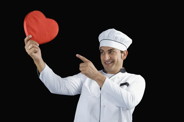 Chef che punta verso un regalo a forma di cuore — Foto Stock