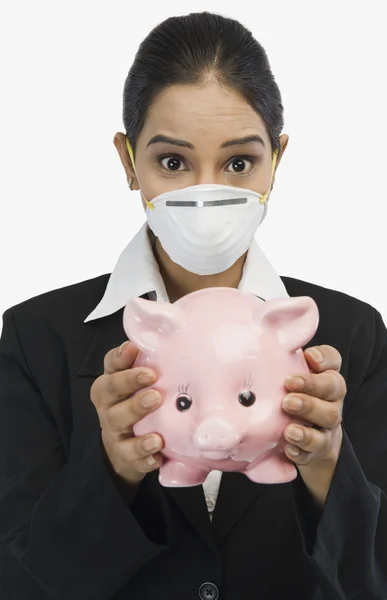 Affärskvinna bär mask och hålla en spargris — Stockfoto