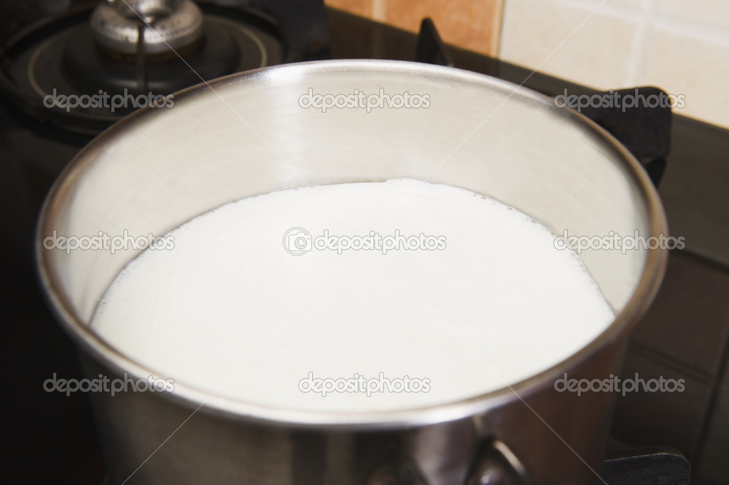 Milk in a saucepan on a gas stove burner Stock Photo by ©imagedb_seller