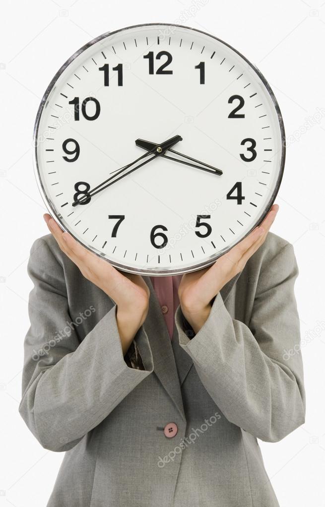 Businesswoman hiding her face with a clock