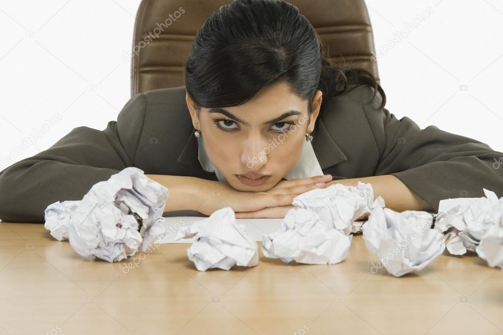 Businesswoman staring crumpled papers on her desk