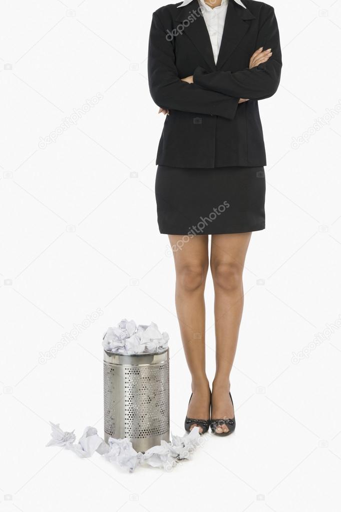 Businesswoman standing in front of a wastepaper basket