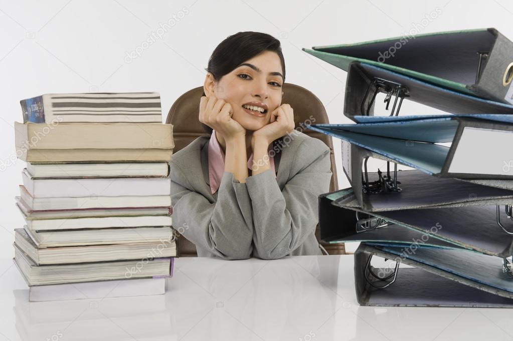 Stack of books and binders in front of a businesswoman