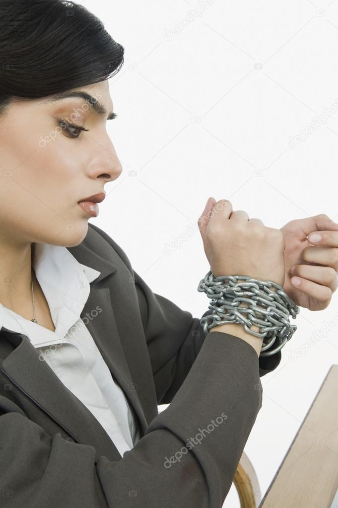 Businesswoman's hands tied up with a chain