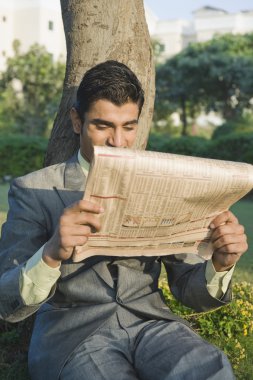 işadamı bir parkta bir gazete okuyor
