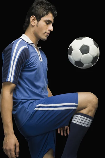 Футболист, тренирующийся с футбольным мячом — стоковое фото