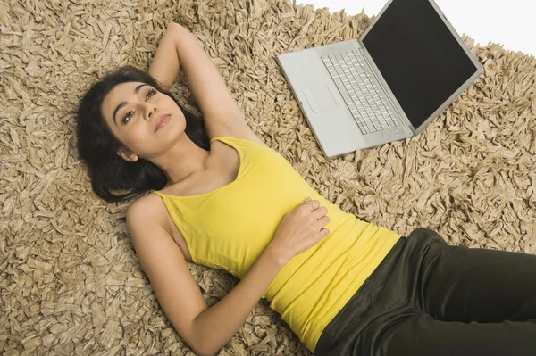 Frau liegt mit Laptop auf Teppich — Stockfoto