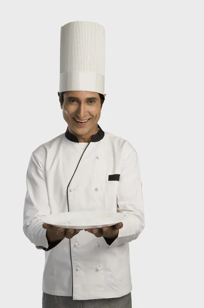 Chef segurando um prato e sorrindo — Fotografia de Stock