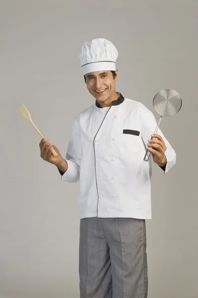 Chef segurando uma peneira e uma colher de madeira — Fotografia de Stock