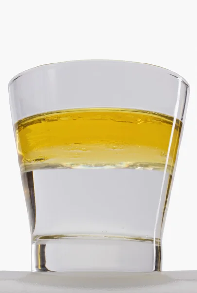 Öl schwimmt in einem Glas auf der Wasseroberfläche — Stockfoto
