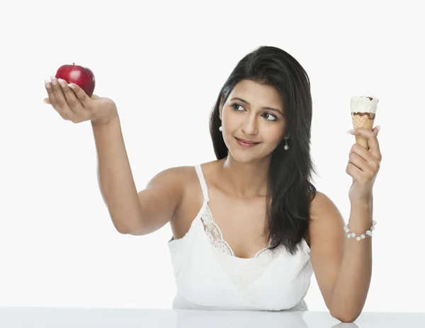 Mulher comparando um cone de sorvete com uma maçã — Fotografia de Stock