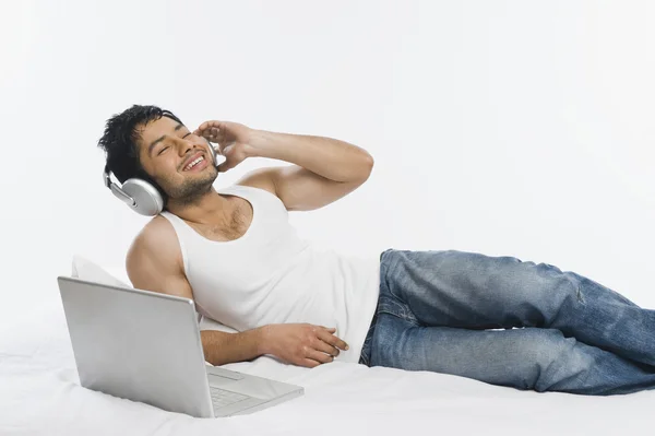 Man listening to headphones with a laptop — Stock Photo, Image